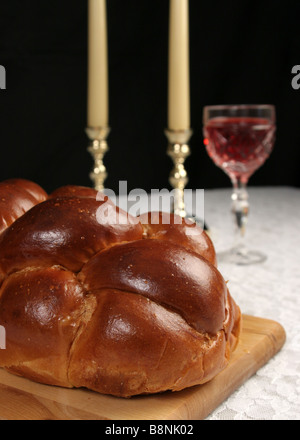 Eine Nahaufnahme Foto Challah Brot für Schabbat mit Wein und Kerzen im Hintergrund vertikal über schwarz Stockfoto