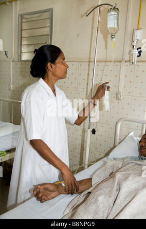 Krankenschwester hält Hand des Patienten und setzt eine Intraveinous Tropf auf der allgemeinen Abteilung der New Civil Hospital, Surat. Gujarat. Indien Stockfoto