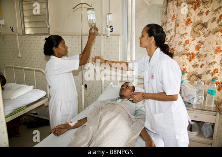 Auf der allgemeinen Abteilung der New Civil Hospital, Surat eingerichtet Krankenschwestern ein Intraveinous Tropf zu einem Patienten. Gujarat. Indien. Stockfoto