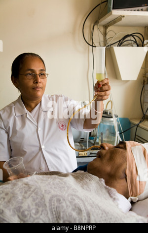 Krankenschwester Fütterung ein sehr kranken Patienten, wenn ein Rohr auf Intensivstation des New Civil Hospital, Surat. Gujarat. Indien. Stockfoto