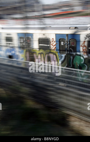 schnelle u-Bahn-Zug mit Graffiti-Kunst auf Schienen in Stadt bedeckt Stockfoto