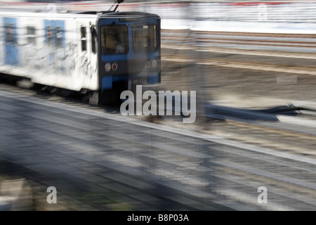 schnelle u-Bahn-Zug mit Graffiti-Kunst auf Schienen in Stadt bedeckt Stockfoto