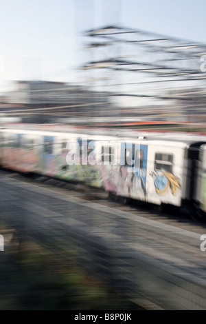 schnelle u-Bahn-Zug mit Graffiti-Kunst auf Schienen in Stadt bedeckt Stockfoto