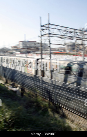 schnelle u-Bahn-Zug mit Graffiti-Kunst auf Schienen in Stadt bedeckt Stockfoto
