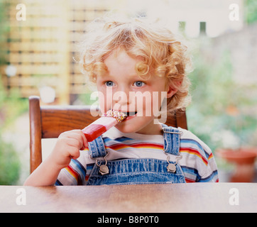 Der blonde Junge isst Eis Stockfoto