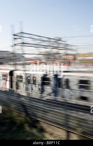 schnelle u-Bahn-Zug mit Graffiti-Kunst auf Schienen in Stadt bedeckt Stockfoto