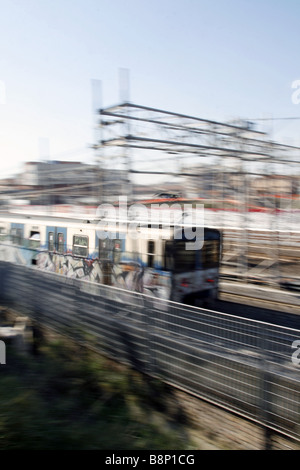 schnelle u-Bahn-Zug mit Graffiti-Kunst auf Schienen in Stadt bedeckt Stockfoto