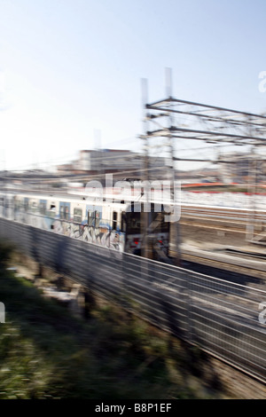 schnelle u-Bahn-Zug mit Graffiti-Kunst auf Schienen in Stadt bedeckt Stockfoto
