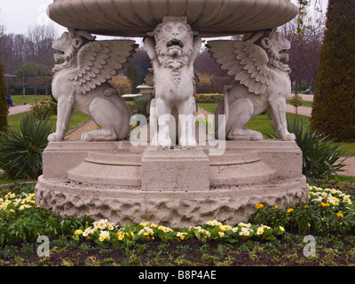 Der Springbrunnen aus Griffin Tazza oder Lion Vase aus Stein, umgeben von Primrosen im frühen Frühling im Regents Park, London, Großbritannien Stockfoto