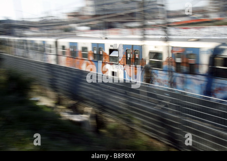 schnelle u-Bahn-Zug mit Graffiti-Kunst auf Schienen in Stadt bedeckt Stockfoto