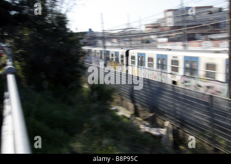 schnelle u-Bahn-Zug mit Graffiti-Kunst auf Schienen in Stadt bedeckt Stockfoto