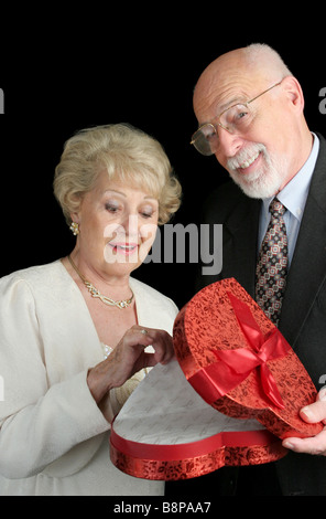 Ein senior Mann sehr stolz auf sich selber für überrascht seine Frau mit Valentine candy schwarzen Hintergrund Stockfoto