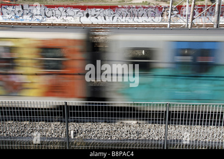 schnelle u-Bahn-Zug mit Graffiti-Kunst auf Schienen in Stadt bedeckt Stockfoto