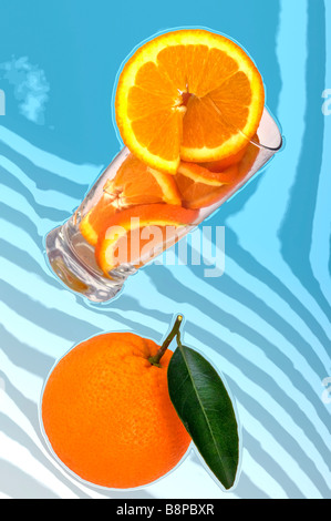 Orange, Glas mit Orangen und Scheibe orange, orange Fruchtsaft auf blauem Hintergrund Stockfoto