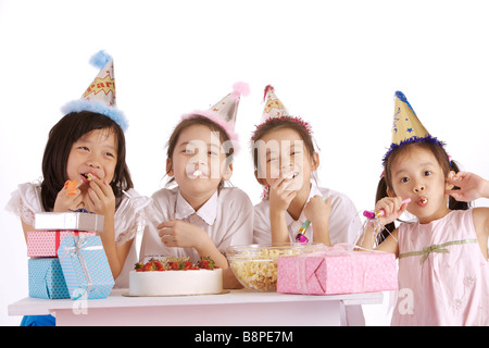 Vier Mädchen lächelnd Geschenke und Schüssel Popcorn auf Tisch Stockfoto