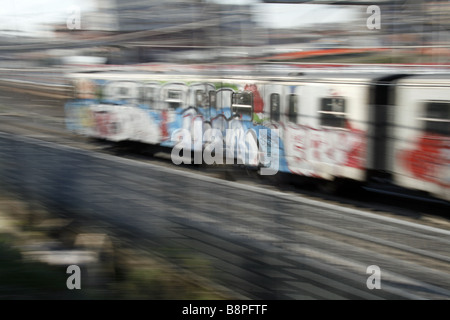 schnelle u-Bahn-Zug mit Graffiti-Kunst auf Schienen in Stadt bedeckt Stockfoto