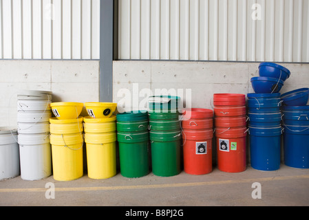 Mehrfarbige Mülltonnen und recycling-Behälter gestapelt entlang Wand Stockfoto