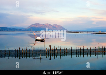 Landschaft bei Sonnenaufgang in Mesologi-kleine hölzerne weiße Fischerboot liegt auf dem ruhigen Wasser der Lagune. Stockfoto