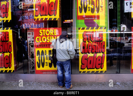 Der New York City Store schließt den Verkauf ab. Mann, der auf der Straße steht und im Schaufenster die reduzierten Liquidationspreise ansieht. Geschäft geschlossen. Stockfoto