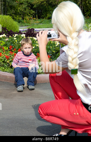 Eine junge Frau fotografiert seinen kleinen Sohn im park Stockfoto