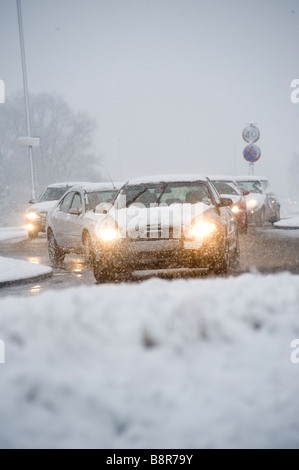 Autos fahren langsam auf einer verschneiten Straße während der morgendlichen Rushhour im Winter in England Stockfoto