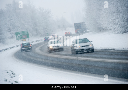 Autos fahren langsam auf einer verschneiten Straße während der morgendlichen Rushhour im Winter in England Stockfoto