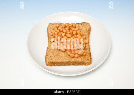 Platte Teller Bohnen auf Toast auf einem abgestuften blauen Studio-Hintergrund Stockfoto