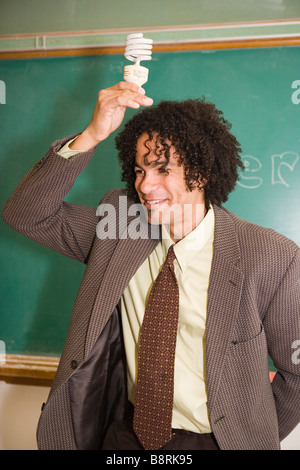 afrikanische amerikanische Lehrer in der öffentlichen Schule halten eine Energie effiziente kompakte Leuchtstoff Glühlampe auf dem Kopf Stockfoto