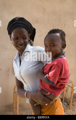 Portrait einer jungen smiley Senegalesische Mutter ihren Sohn Holding auf ihren Hüften Stockfoto