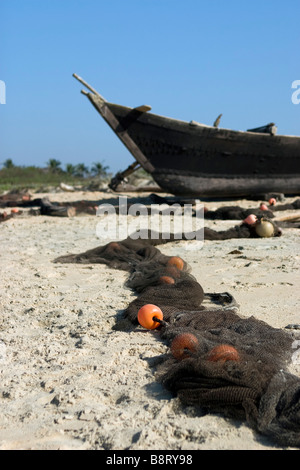 Trocknung Fischernetz am Strand in der Nähe von Boot bei Sonnenaufgang Varca Beach, Goa, Indien. Stockfoto