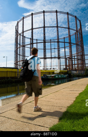 Ein Mann geht auf dem Regent Canal Weg im Osten Londons vorbei an einer stillgelegten Gas-Werke-Struktur Stockfoto