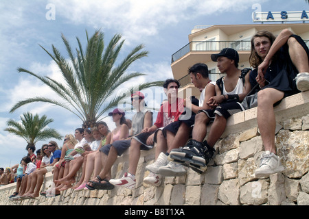 Zuschauer bei Veranstaltung sitzen auf der Mauer am Strand, Spanien, Balearen, Mallorca, Palma Stockfoto