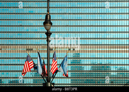 Laternenpfahl mit UN und USA Flaggen vor der Glasfassade der Hauptsitz der Vereinten Nationen, UNO, New York, USA Stockfoto