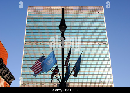 Laternenpfahl mit UN und USA Flaggen vor der Glasfassade der Hauptsitz der Vereinten Nationen, UNO, New York, USA Stockfoto