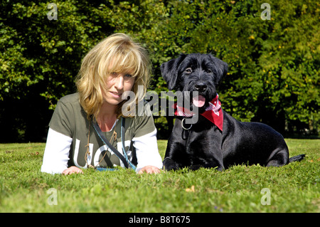 Riesenschnauzer (Canis Lupus F. Familiaris), Frau und Riesenschnauzer im Rasen liegen Stockfoto