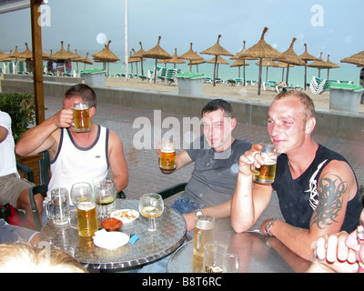 drei junge Männer am Strand-Promenade sitzen und Biertrinken, Spanien, Balearen, Mallorca Stockfoto