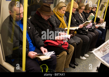 Menschen sitzen und lesen auf einer Londoner U-Bahn. Stockfoto