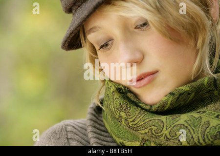 verträumte junge Blondine mit Kappe Stockfoto