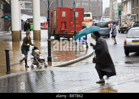 Eine ältere Dame kreuzt die Straße im Regen Guildford, Surrey, England. Stockfoto