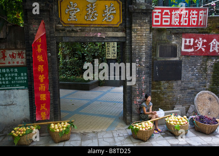 Ein Heranwachsenden Mädchens sellin Pfirsiche vor einer christlichen Kirche in der Stadt Chongqing, China. Stockfoto