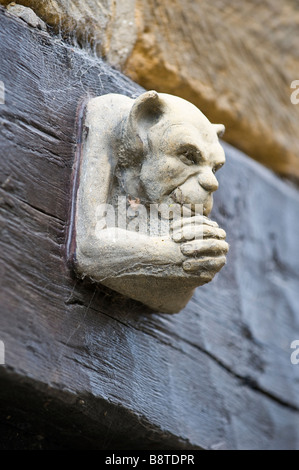 Gargoyle über einer Tür umklammerte seine Hände nach unten schauen. Stockfoto