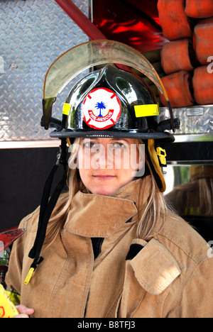 Weibliche Feuerwehrmann Rettungssanitäter in Uniform und Helm posiert vor Feuerwehrauto Stockfoto