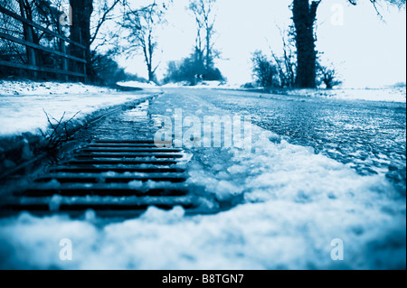 Ein am Straßenrand Abfluss mit schmelzender Schnee Stockfoto