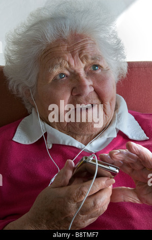 Ältere Dame iPOD AUDIO BUCH MUSIK PLAYER LERNEN SPRACHE OHRHÖRER ältere Dame mit Ihrem tragbaren Player für eine Vielzahl von digitalen Audio Media Dateien Stockfoto