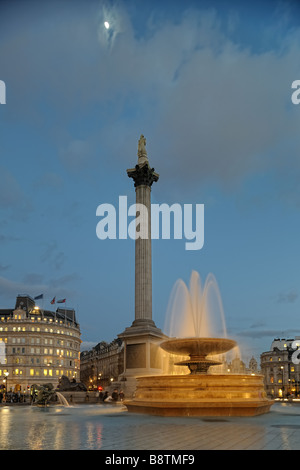 Trafalgar Square-Brunnen in der Abenddämmerung mit Nelson s Spalte im Hintergrund beleuchtet Stockfoto