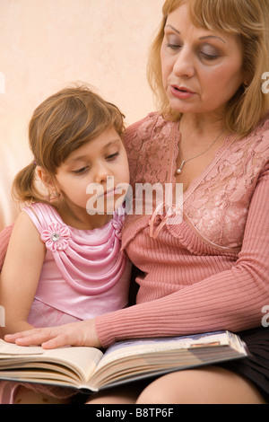 Enkelin und Großmutter sitzt auf einem Sofa und lesen Buch Stockfoto