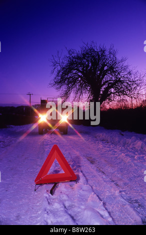 Fahrzeug auf Schnee gebunden Landstraße Gefahr Warndreieck in der Dämmerung in der Nähe von Leeds Yorkshire UK Stockfoto