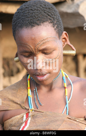 Afrika-Tansania-Mitglieder des Stammes Datog Frau in traditioneller Kleidung Perlen und Ohrringe Schönheit Narben rund um ihre Augen Stockfoto