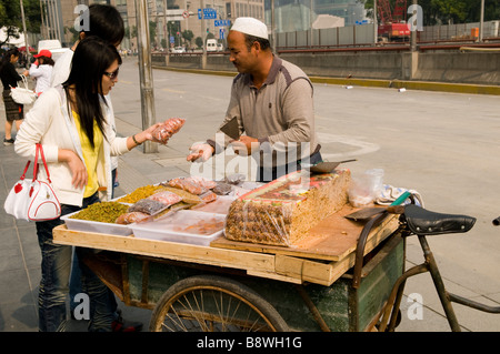 Ein Uyghur Muslim aus Xinjiangs verkauft traditionelle Süßigkeiten und Nüssen in den Straßen von Pudong, Shanghai. Stockfoto