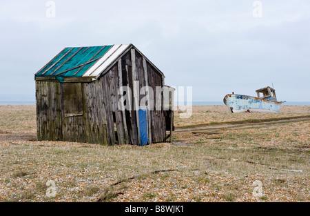 Stillgelegten Holzhütte Hütte und Schuppen und entfernten verlassenen Fischerboot auf dem Kies bei Dungeness in Kent Stockfoto